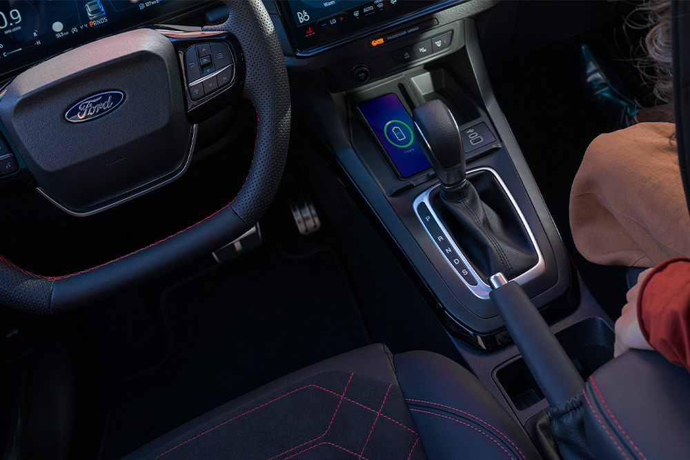 Una vista interior de un automóvil híbrido suave de Ford, incluido el volante y la palanca de cambios automática.
