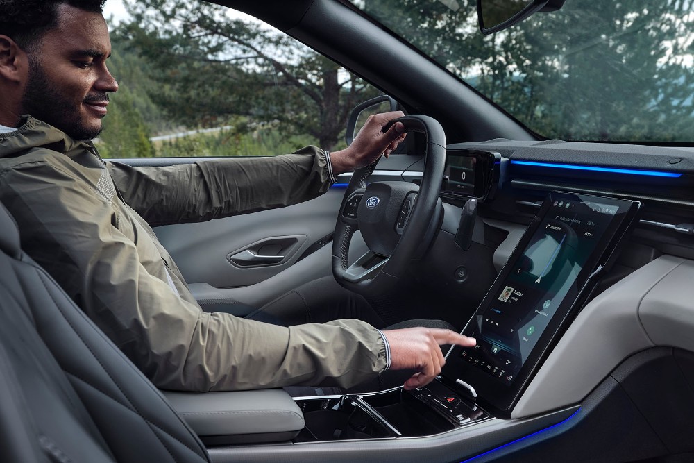 Hombre sentado en el asiento del conductor del Ford Explorer manipulando la pantalla táctil SYNC.