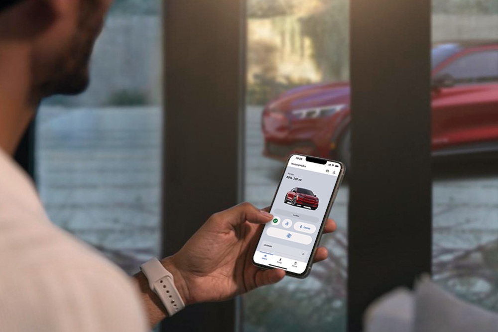 Un hombre comprobando los ajustes de su nuevo Ford Mustang Mach-E mediante las funciones de control a distancia de la aplicación FordPass