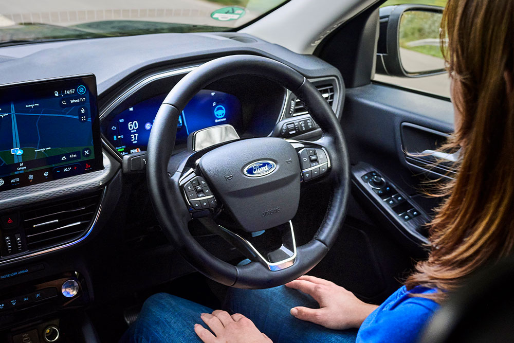 Una mujer en el asiento del conductor de un Kuga equipado con  Ford BlueCruise, con las manos fuera del volante.