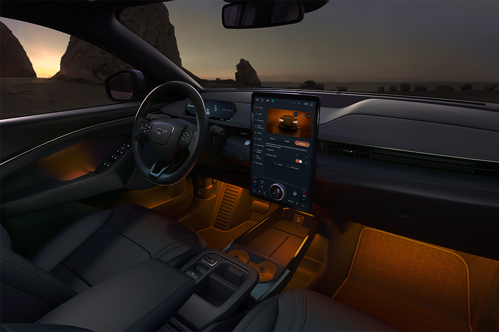 El interior del Ford Mustang Mach-E por la noche, con la pantalla táctil SYNC 4 de 15,5" y la iluminación LED ambiental en color naranja.