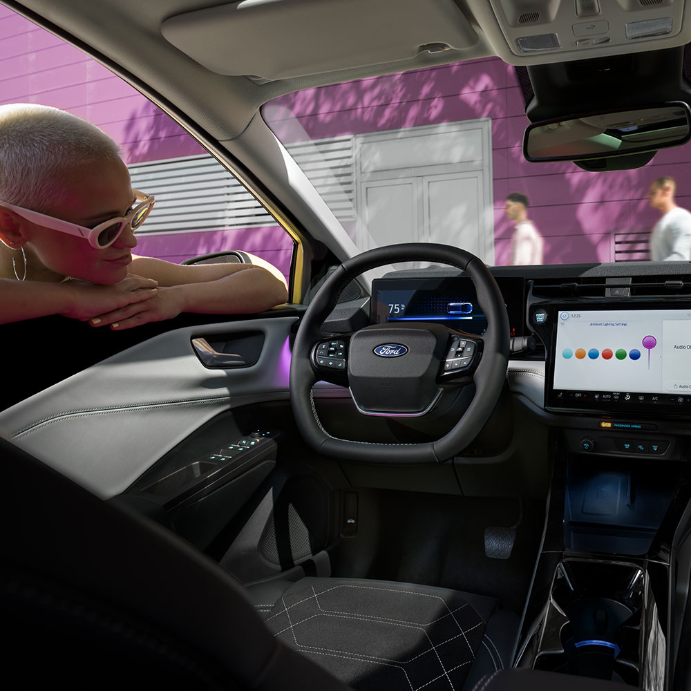 El interior del Ford Puma Gen-E® eléctrico, con una persona mirando la gran pantalla de infoentretenimiento a través de la ventanilla.