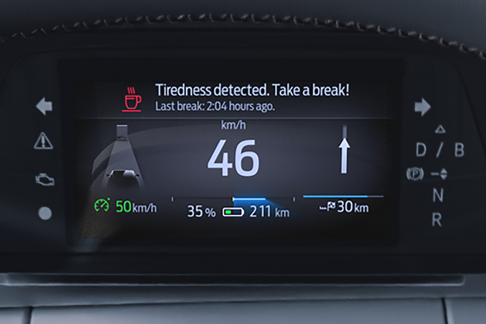 Cuadro de instrumentos digital del Ford Capri mostrando la velocidad del vehículo y un mensaje de alerta al conductor recomendando a este que se tome un descanso.