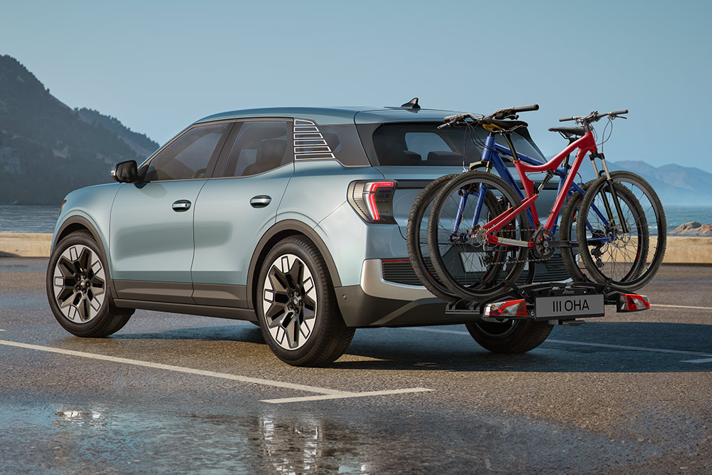 Ford Explorer azul circulando por un camino de tierra, con barras transversales, un portabicicletas de techo y dos bicicletas montadas en el techo.