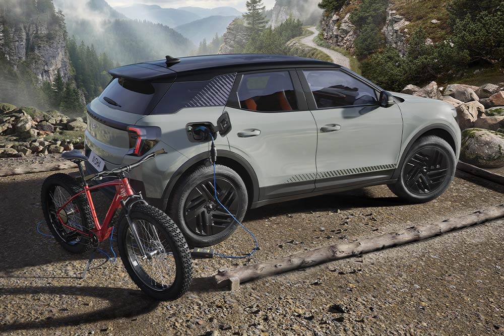 Una bicicleta eléctrica cargando desde una Ford Explorer®, con un paisaje montañoso de fondo.