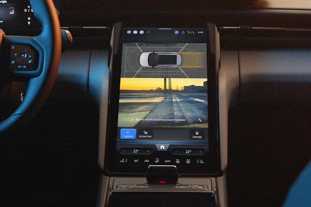 Primer plano de una pantalla táctil digital de un SUV de Ford que muestra el sistema de aparcamiento asistido «Active Park Assist» en uso.
