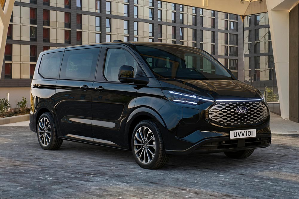Un Ford E-Tourneo Custom negro estacionado frente a un edificio moderno.