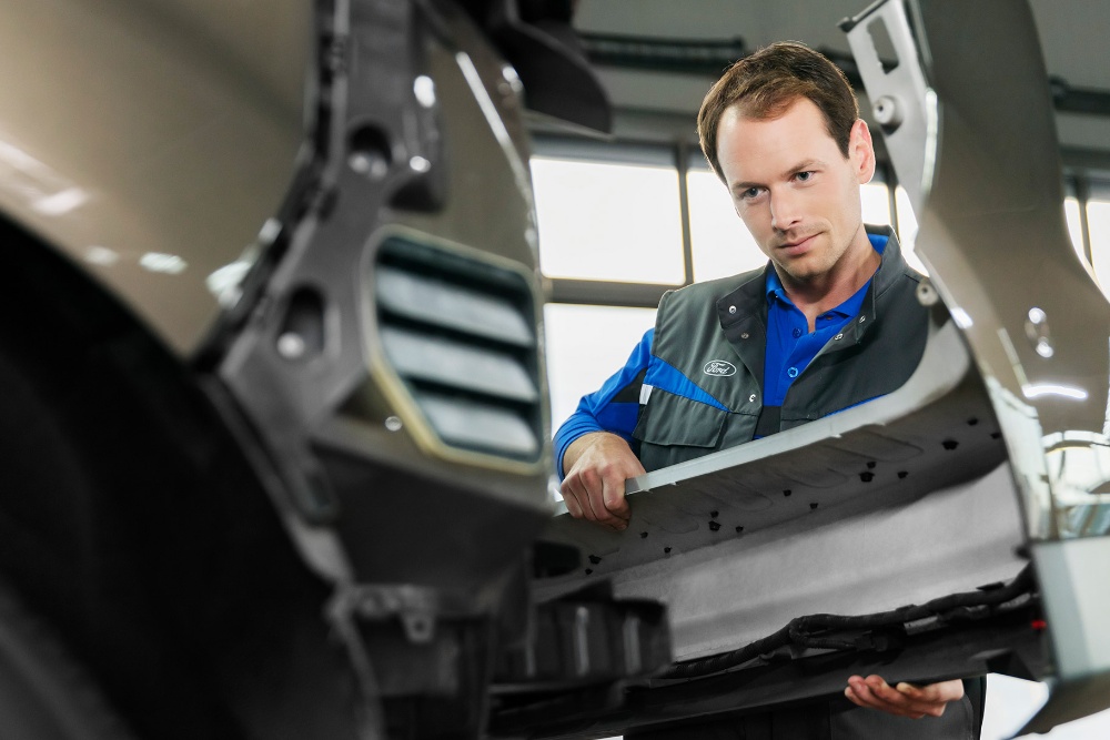 Técnico de servicio de Ford cambiando un parachoques delantero