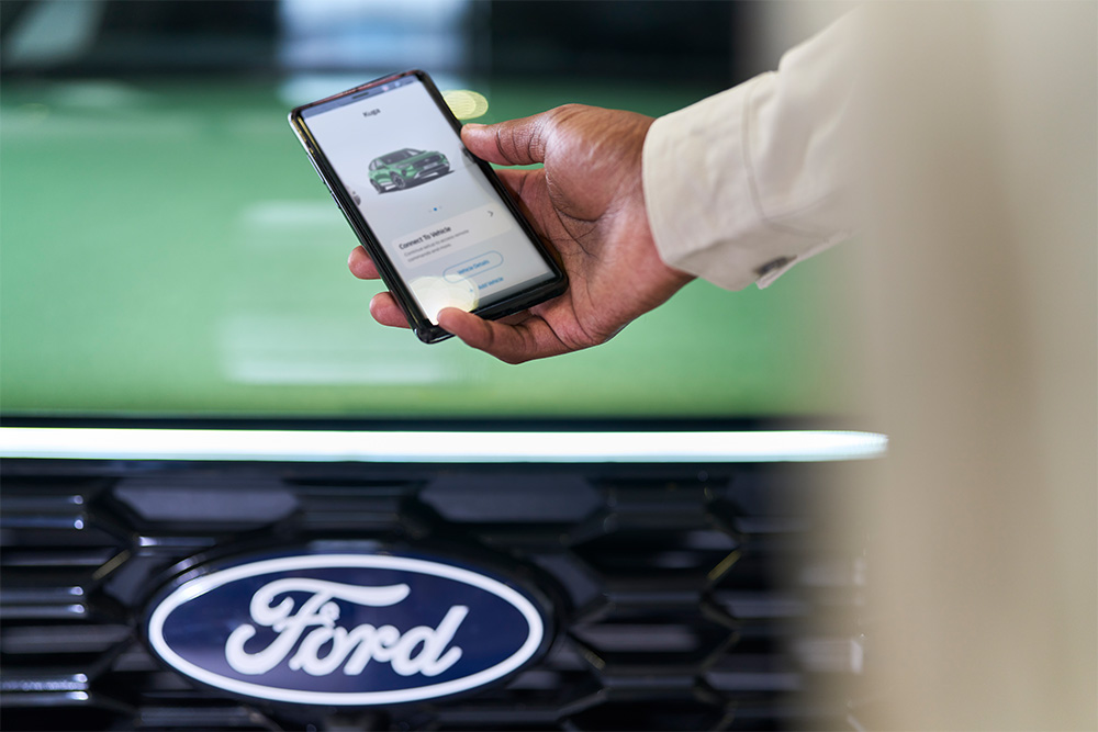 Hombre mirando un smartphone con la aplicación de Ford en pantalla
