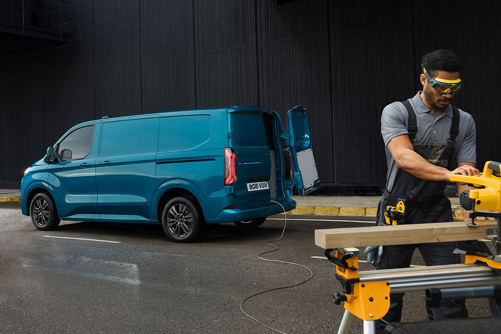 Una furgoneta eléctrica Ford E-Transit Custom azul y una persona usando herramientas eléctricas.