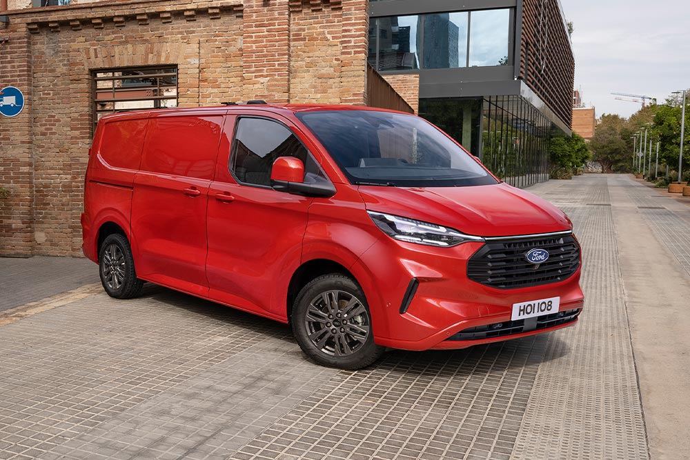 Una furgoneta Ford Transit Custom roja aparcada en una calle de una ciudad.