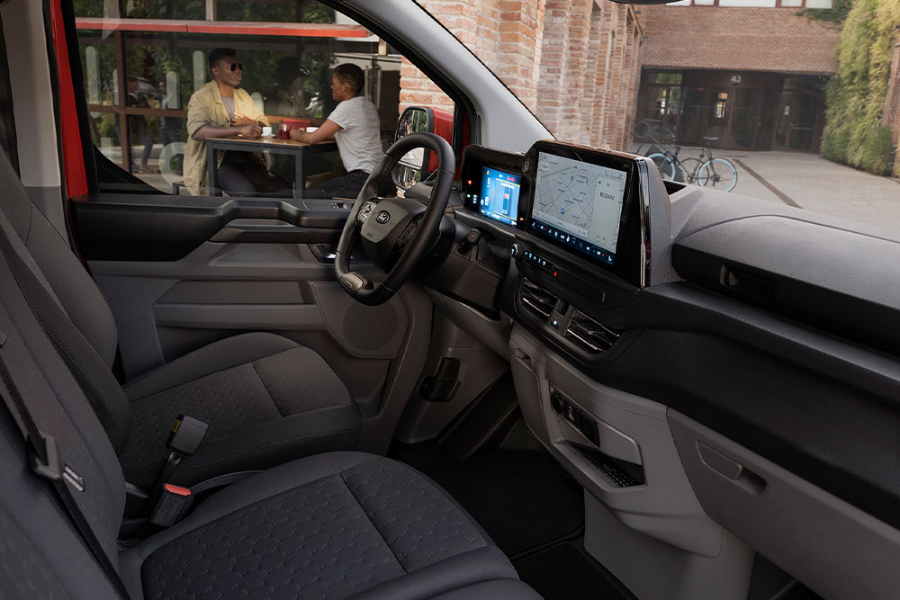 Una persona sentada en el asiento del conductor de una furgoneta eléctrica Ford E-Transit Custom roja.