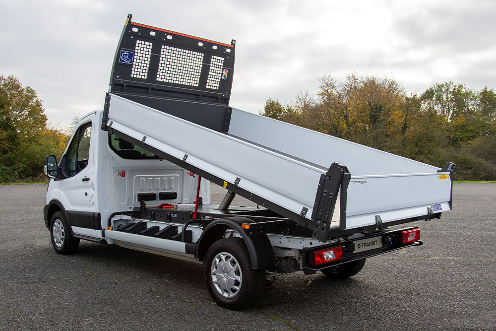  Chasis cabina Ford Pro blanco con plataforma elevada aparcado en un estacionamiento pavimentado.