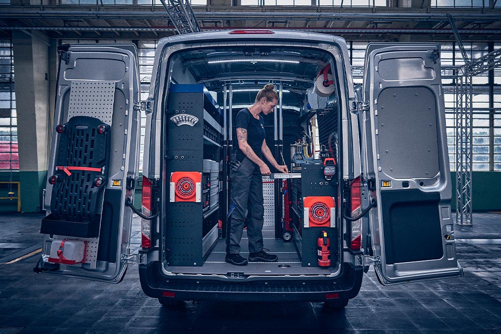 Técnico dentro de la parte trasera de una furgoneta Ford, revisando datos en su portátil.