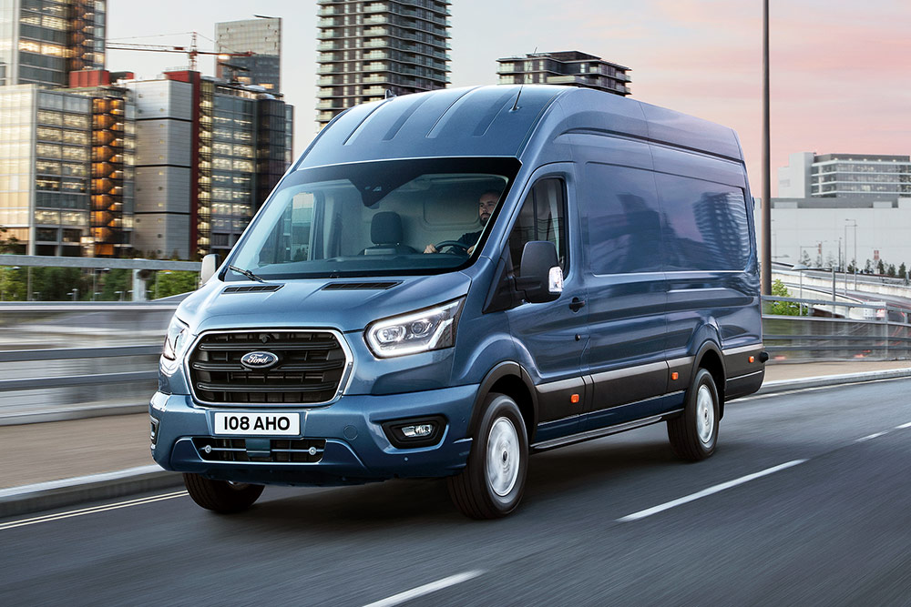 Un Ford Transit cruzando un puente, con un paisaje urbano edificado al fondo.