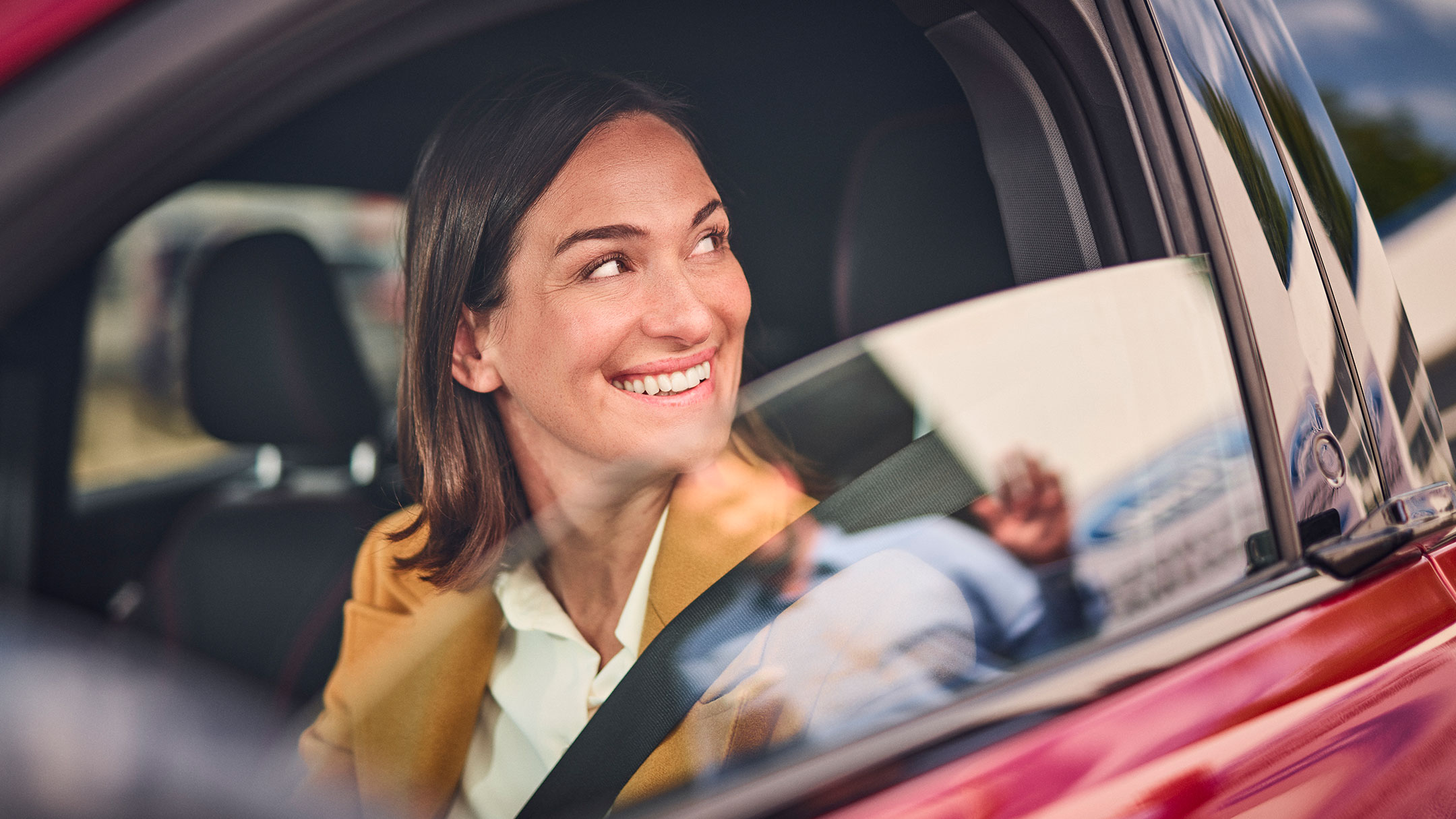 Una persona sonríe sentada en un coche Ford.